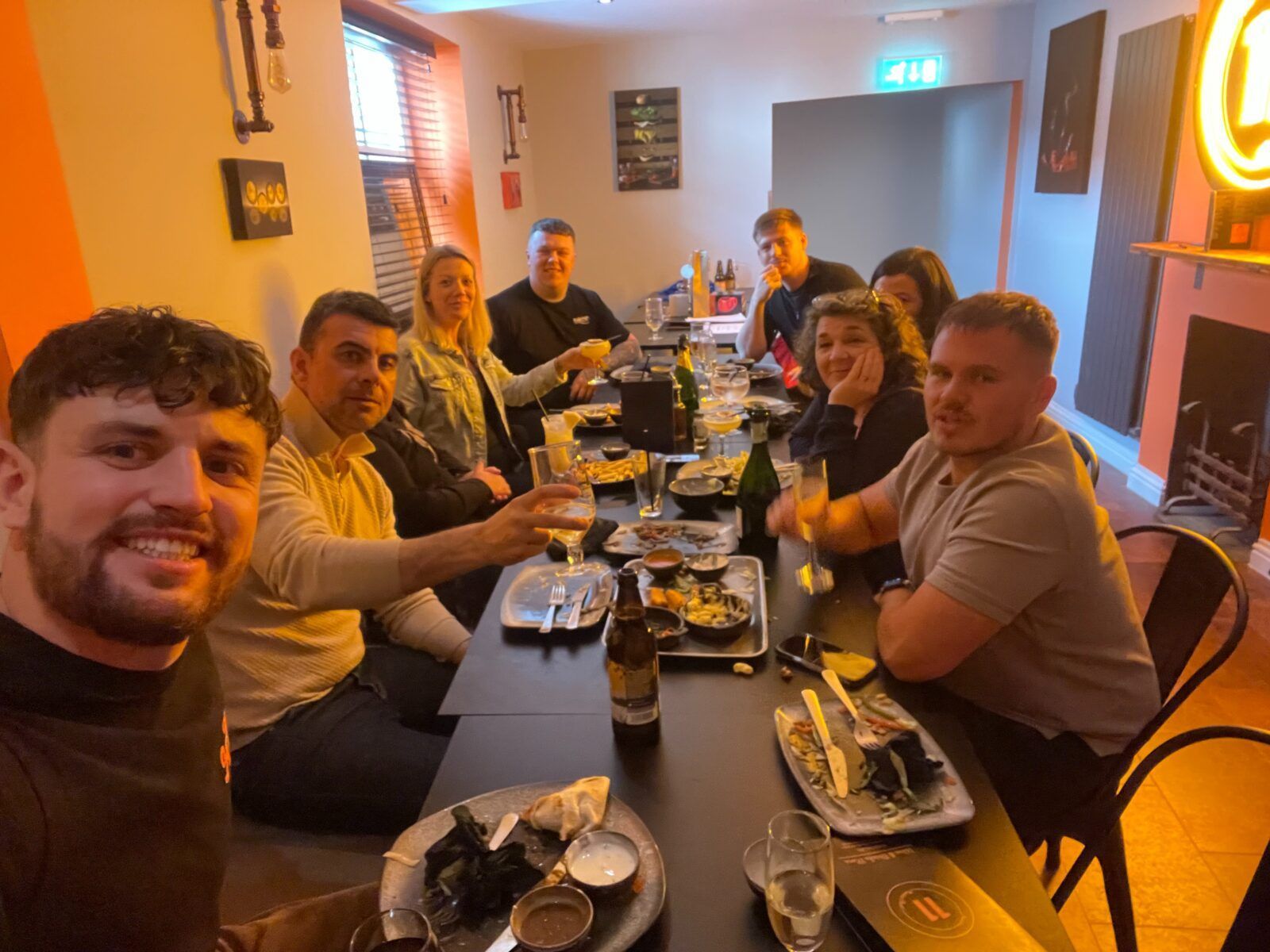 A group of people are sitting at a table with plates of food and drinks.