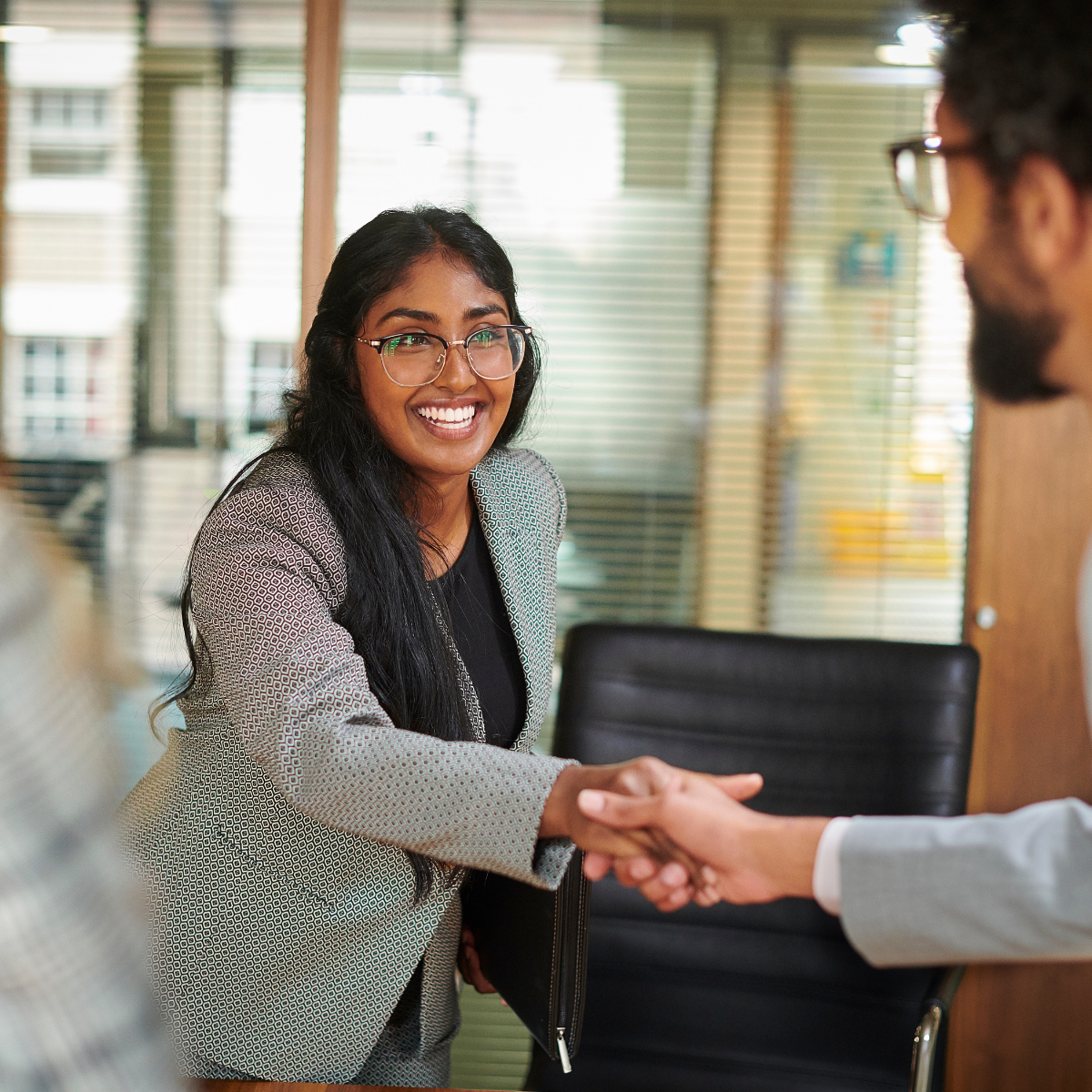 A woman is shaking hands with a man in a conference room.