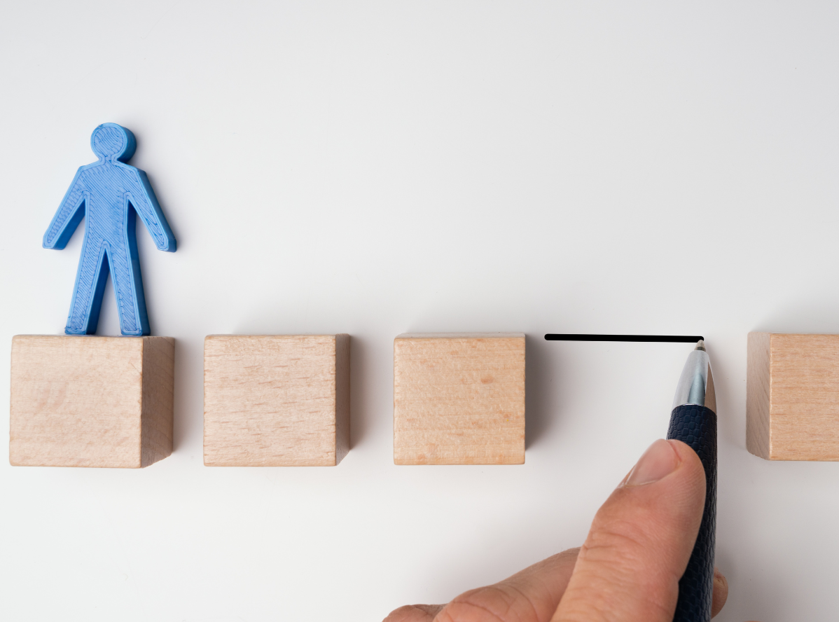 A person is drawing a line between two wooden blocks.