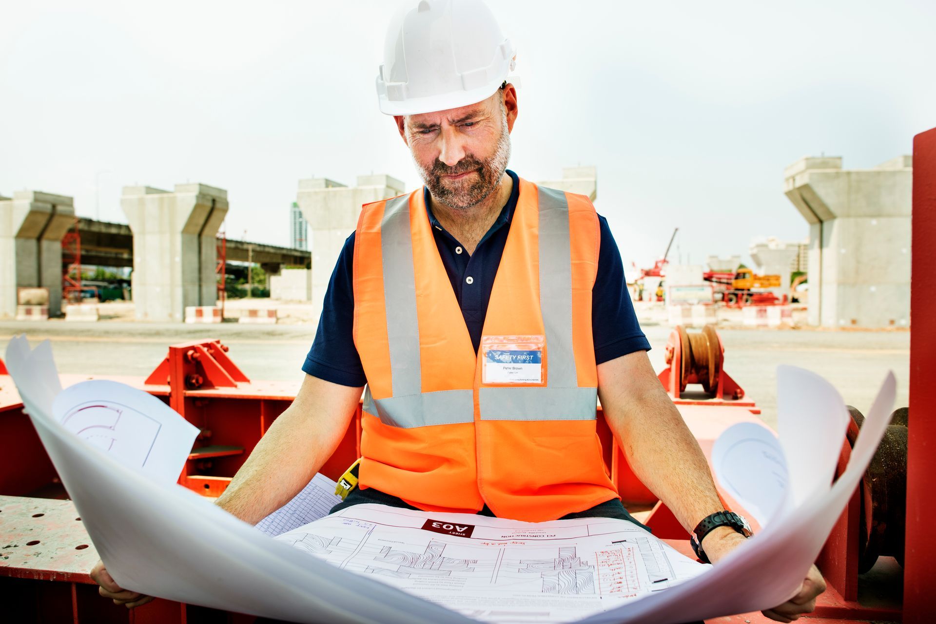 Two men wearing hard hats are looking at a piece of paper