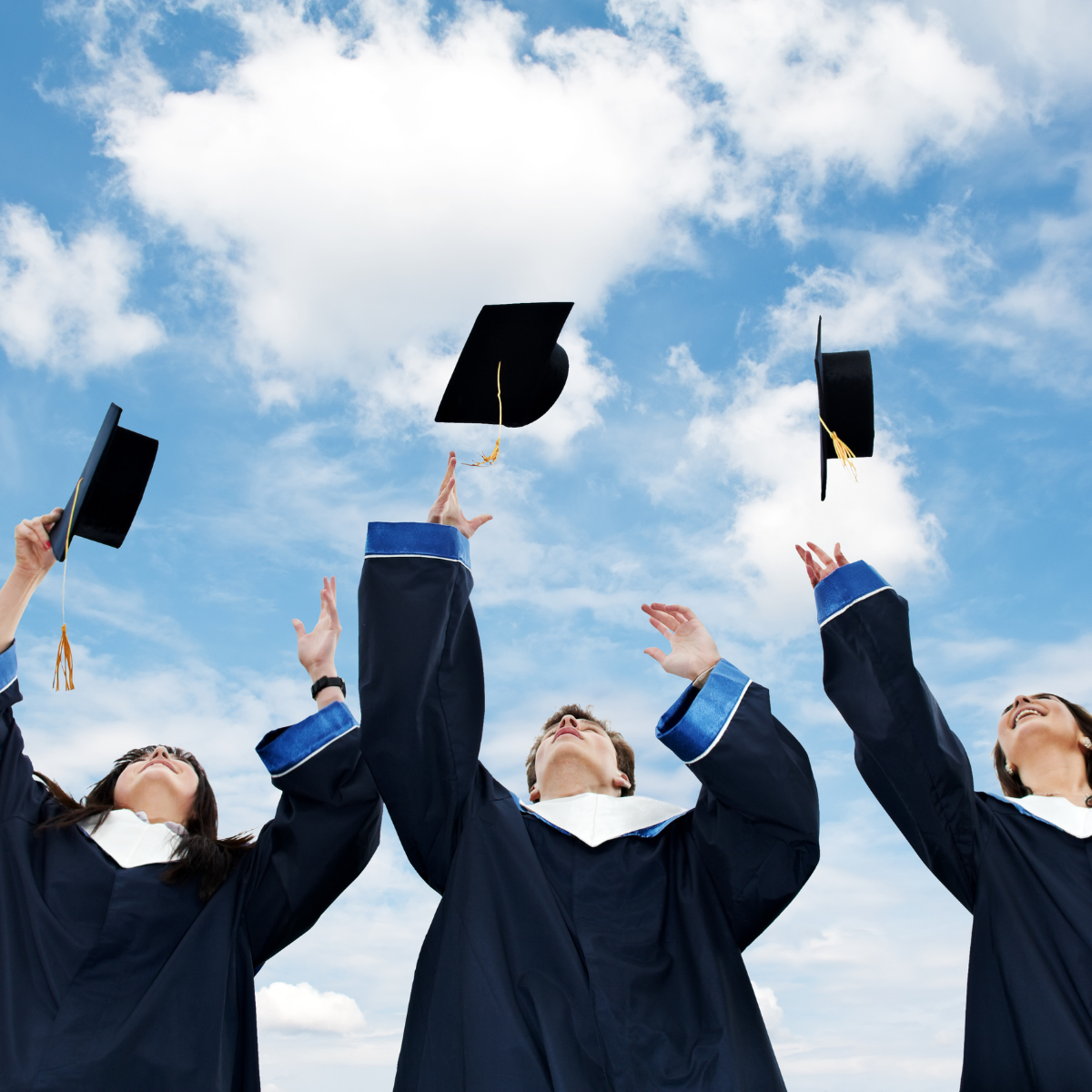 Three graduates are throwing their caps in the air