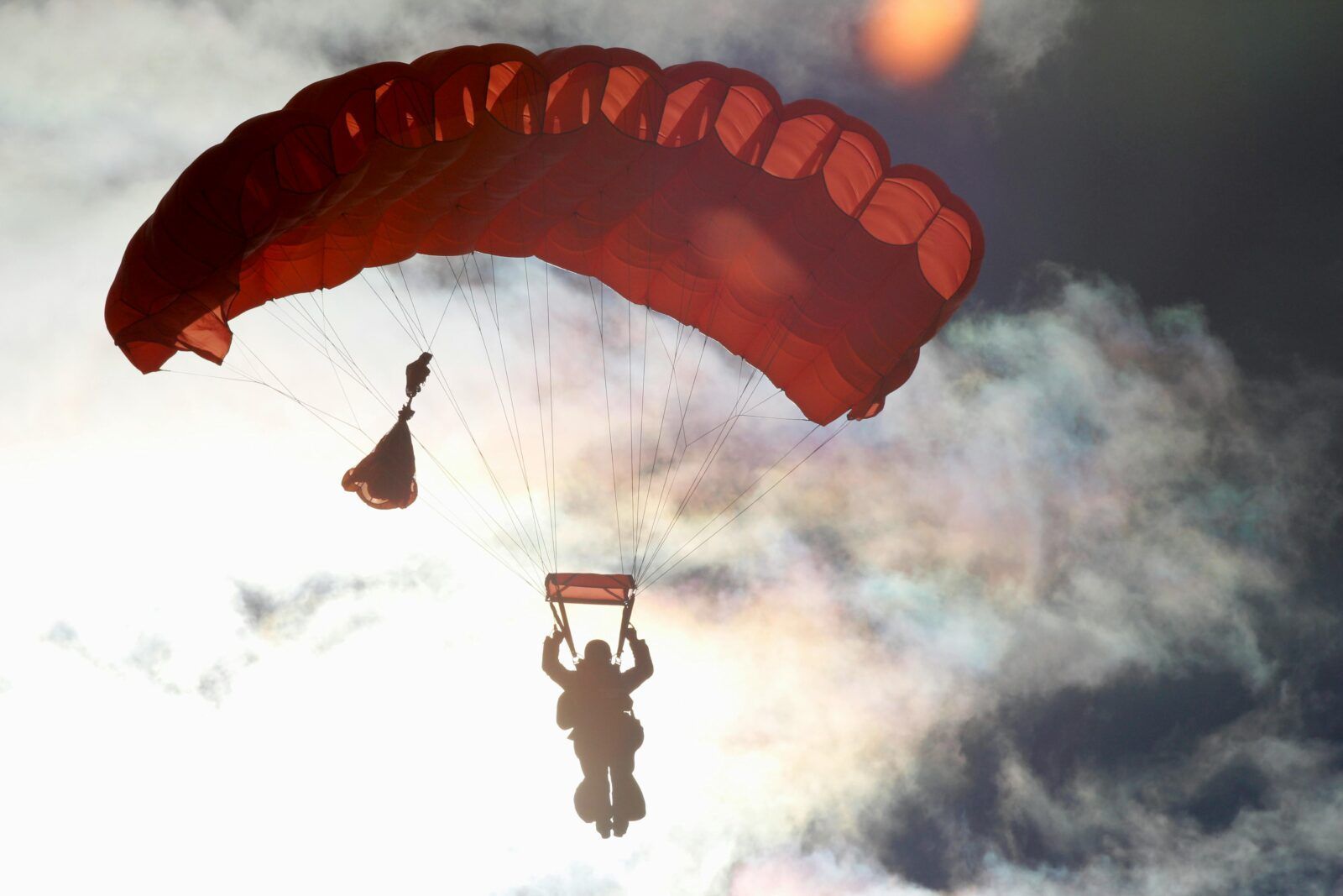 A person is flying through the air with a red parachute