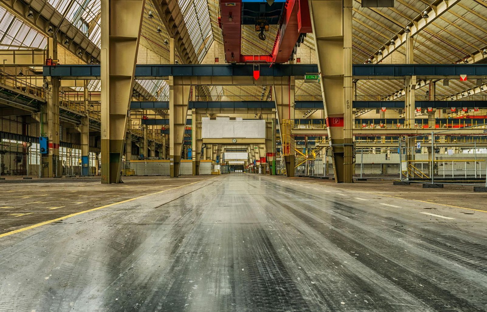 An empty factory with a crane in the middle of it.