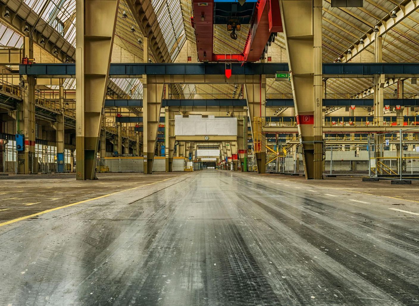 An empty factory with a crane in the middle of it.