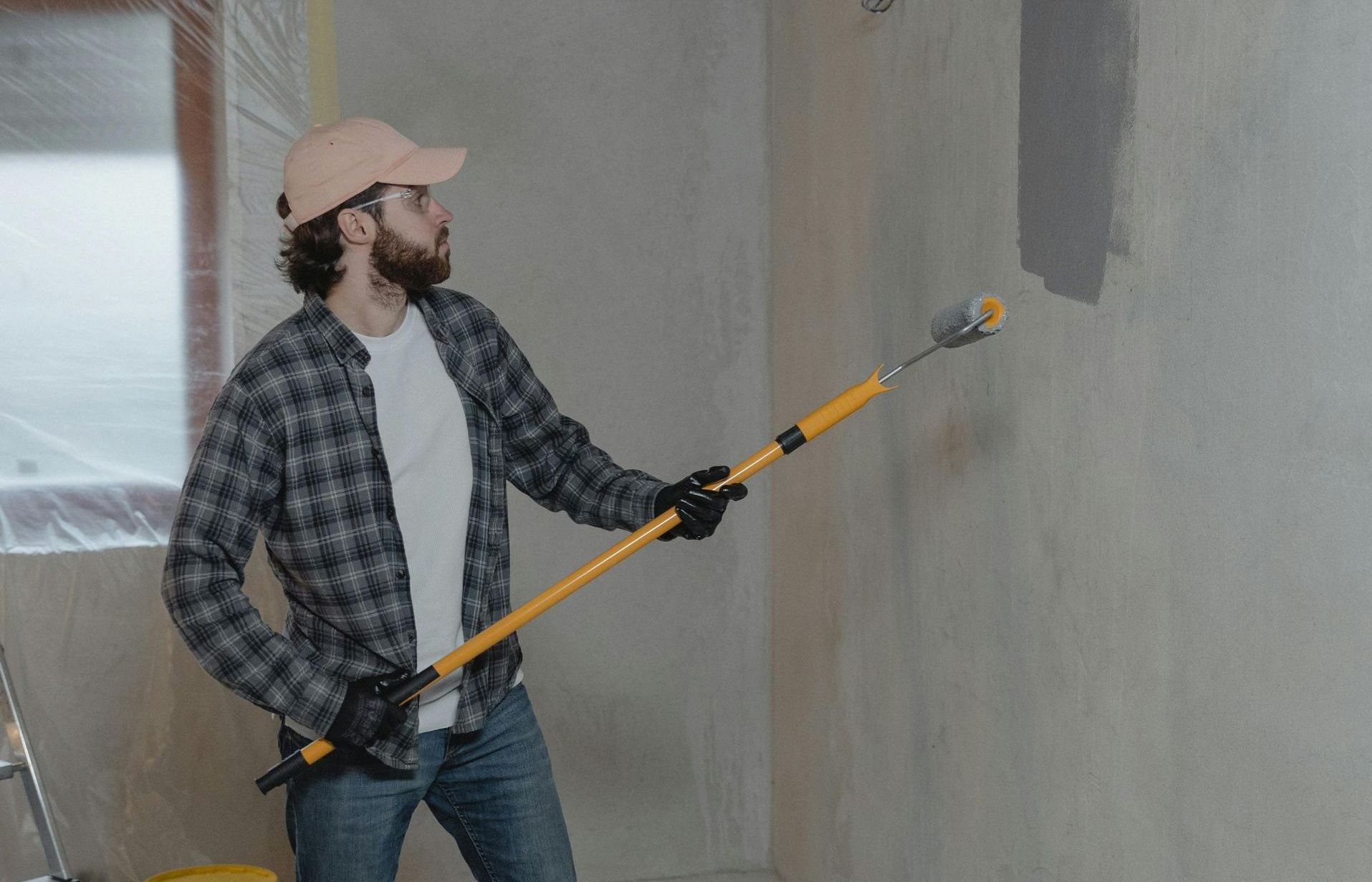A man is painting a wall with a paint roller.