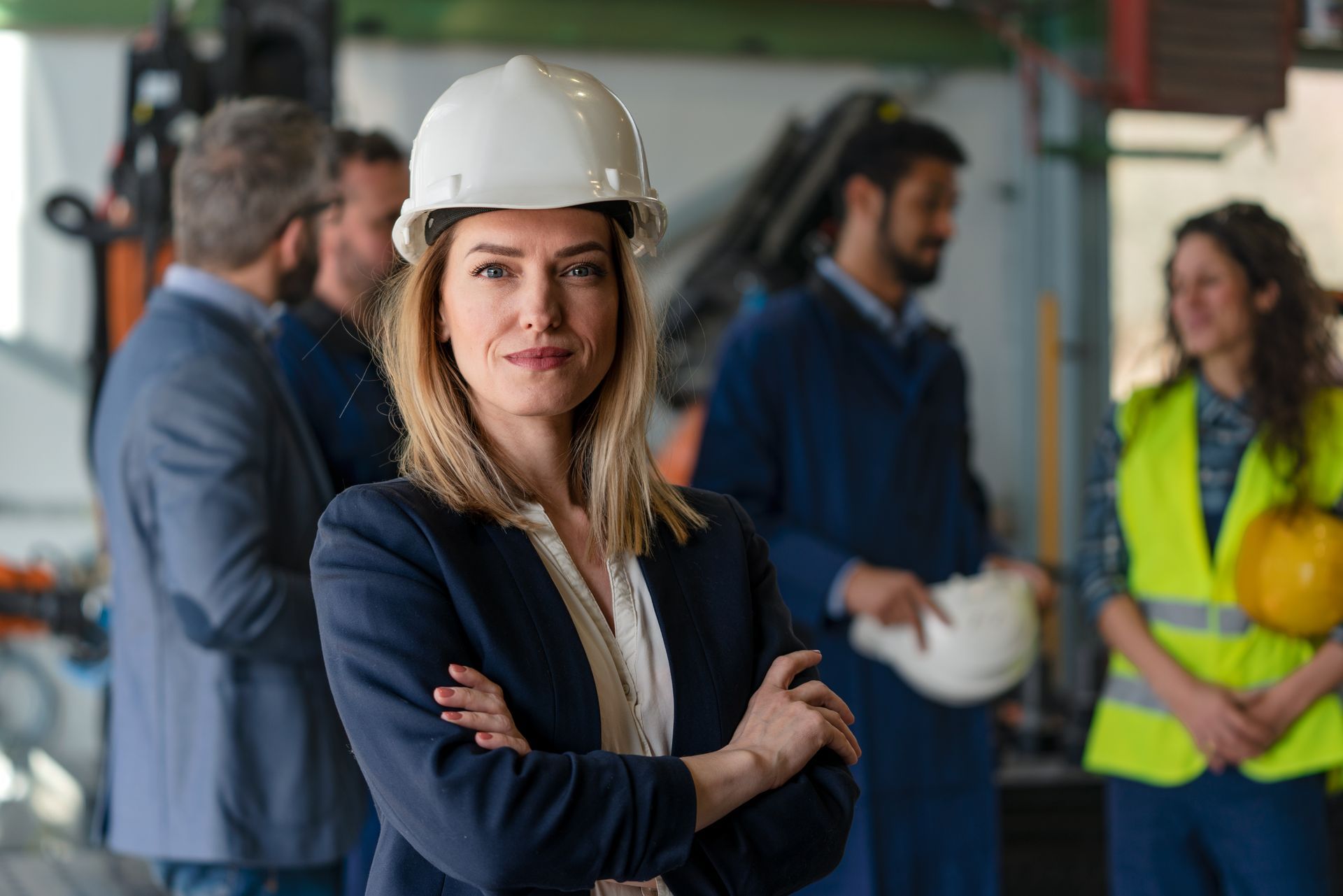 A construction worker wearing a hard hat and headphones is looking at a clipboard.