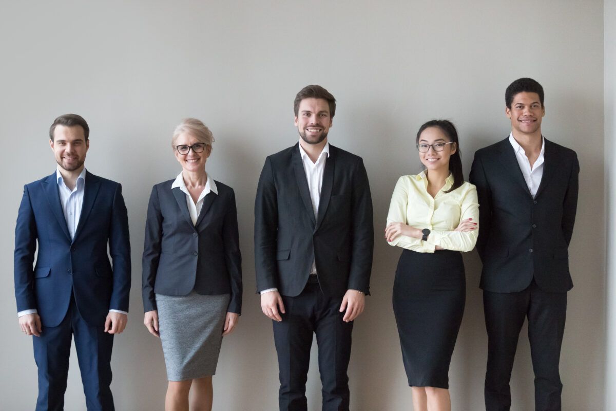 A group of business people are standing next to each other in front of a wall.