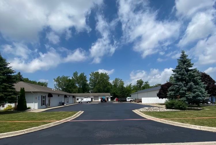 A motel with a lot of cars parked in front of it on a sunny day.