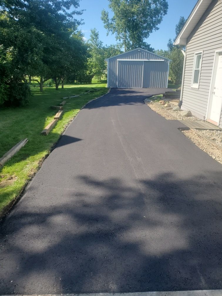 A driveway leading to a house with a shed in the background.