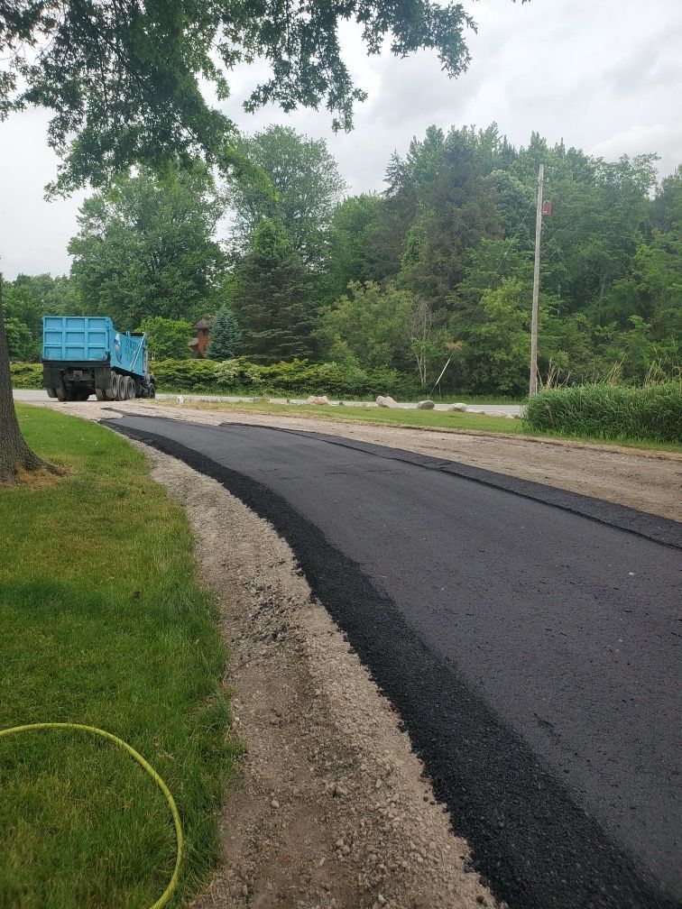 A dump truck is driving down a newly paved road.