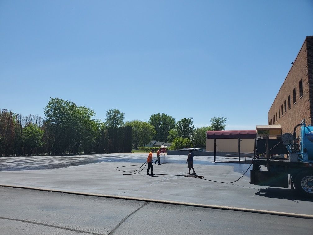 A group of people are working on a parking lot in front of a building.