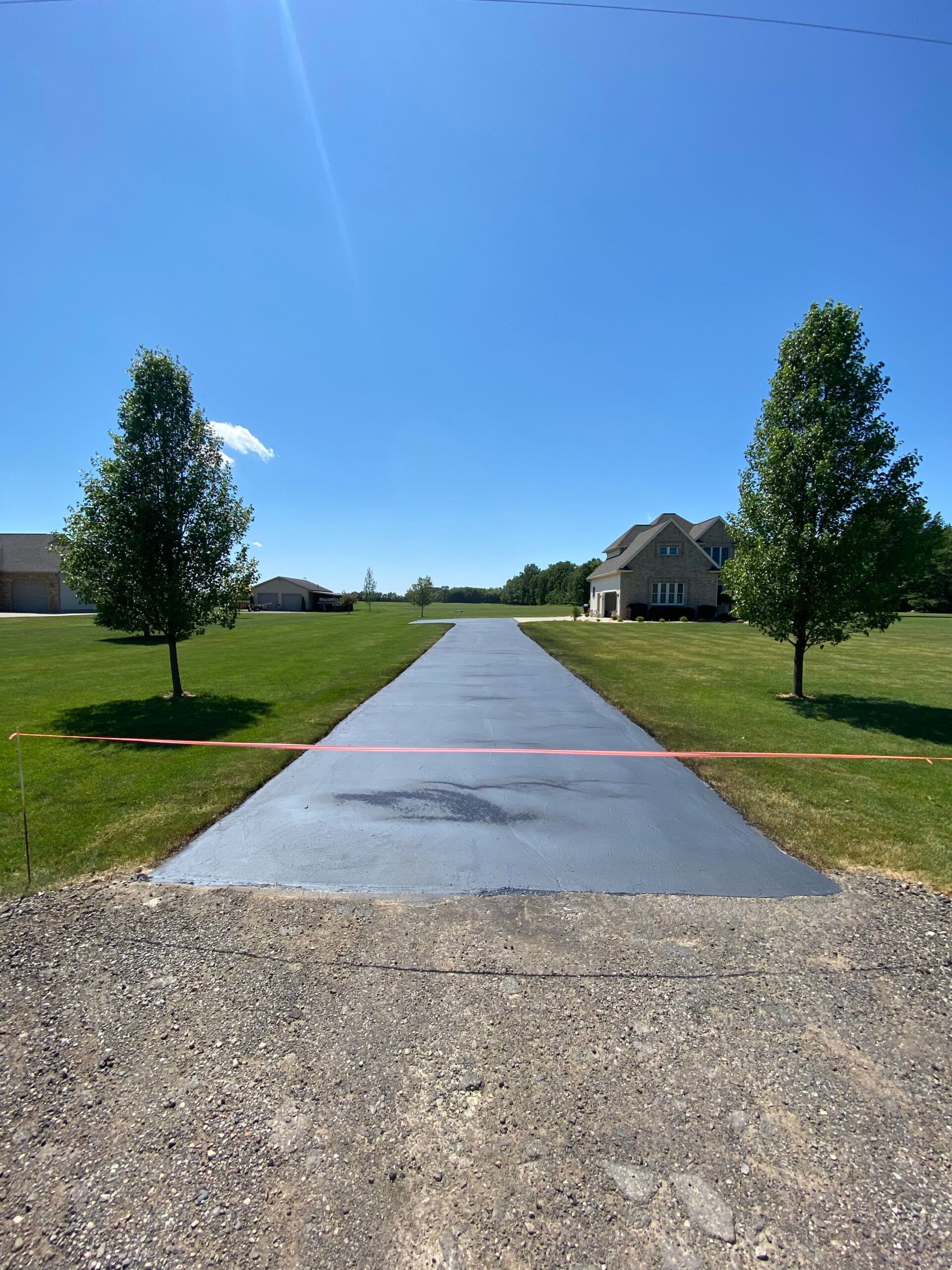 A driveway leading to a house with trees on both sides.