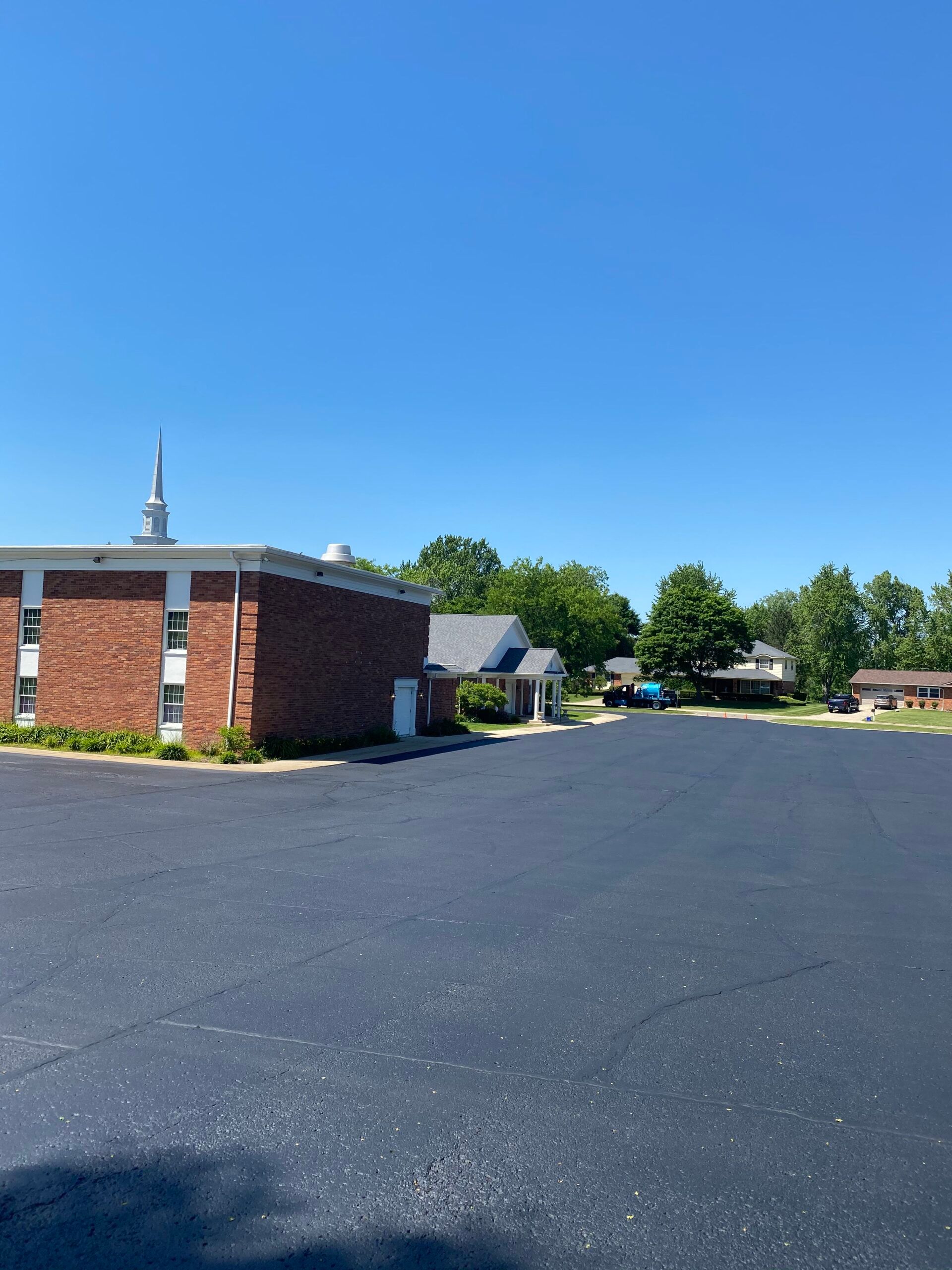 A brick building with a steeple sits in the middle of a parking lot