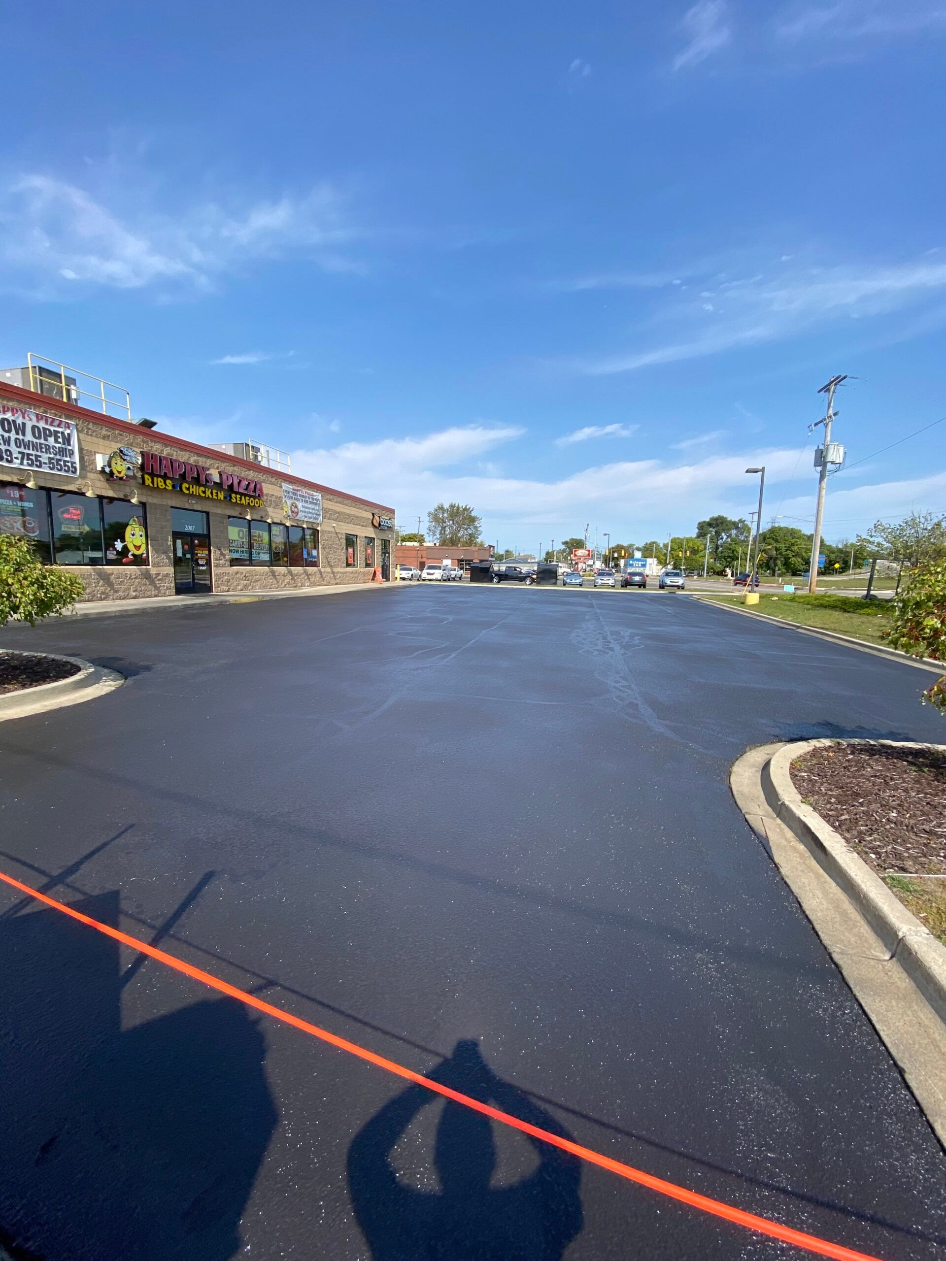 A parking lot with a building in the background and a person taking a picture of it.