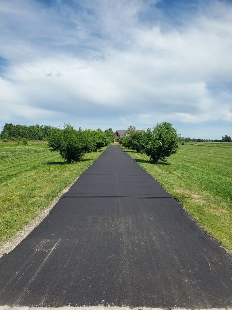 A long road going through a grassy field to a house