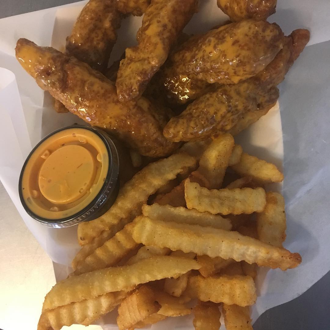 Chicken wings, fries, and dipping sauce in a basket; close-up shot.