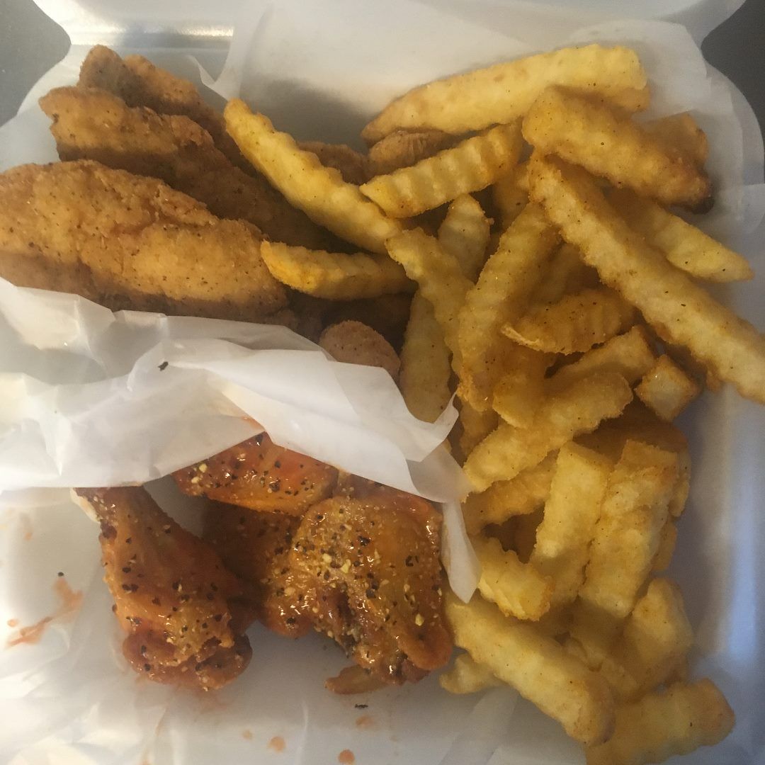 Fried chicken, fries, and wings in a foam container.