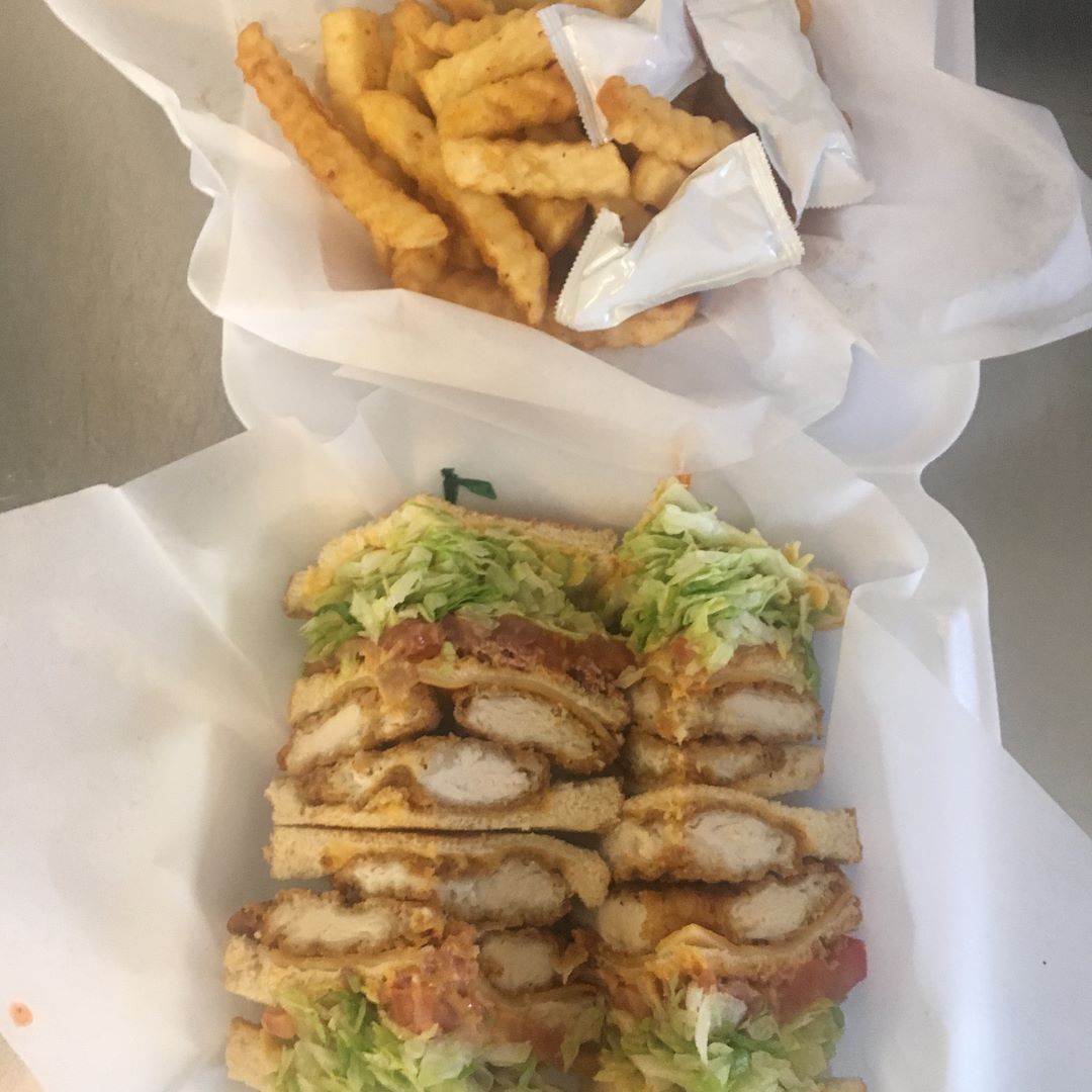 Chicken sandwich and fries in a white container, with ketchup packets.