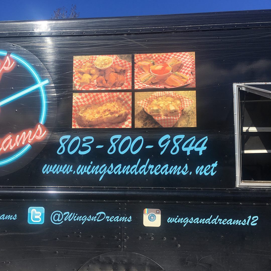 Black food truck with neon sign reading 