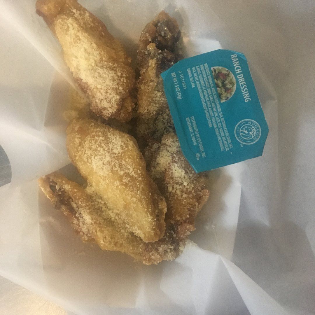 Chicken wings with ranch dressing in a white container.