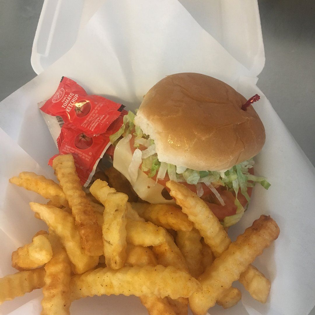 Burger with fries and ketchup in a takeout container.