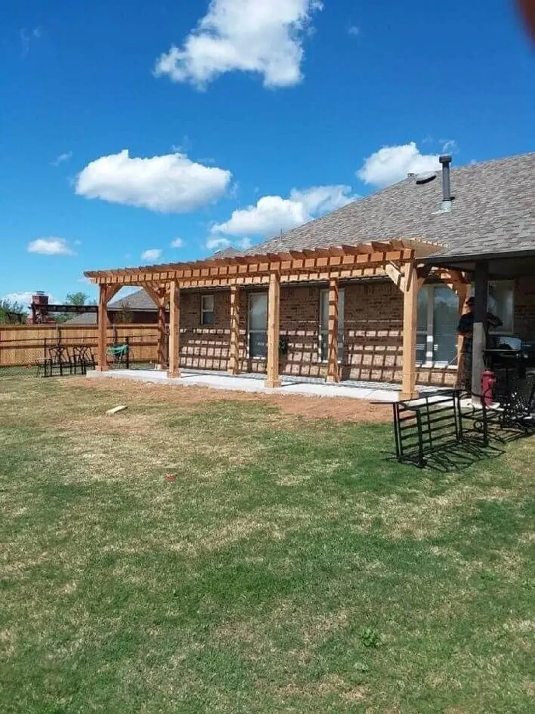 A house with a pergola in the backyard on a sunny day.
