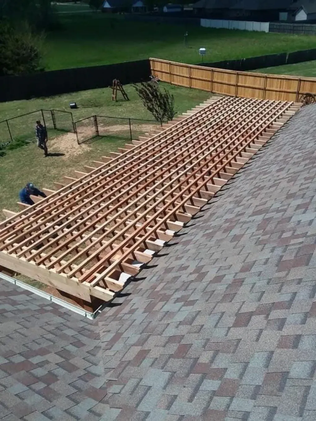 A large wooden structure is being built on top of a brick roof.