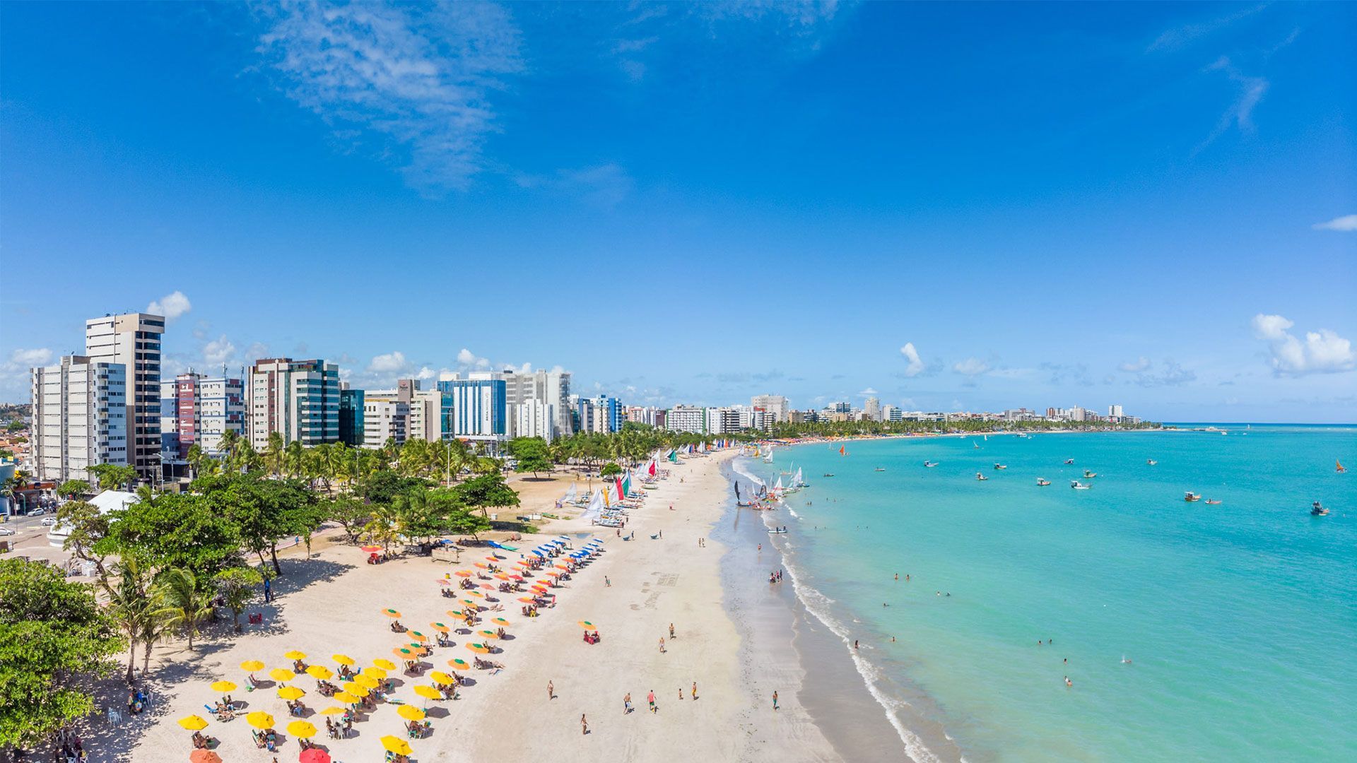Família com os braços estendidos na praia, com o oceano ao fundo.