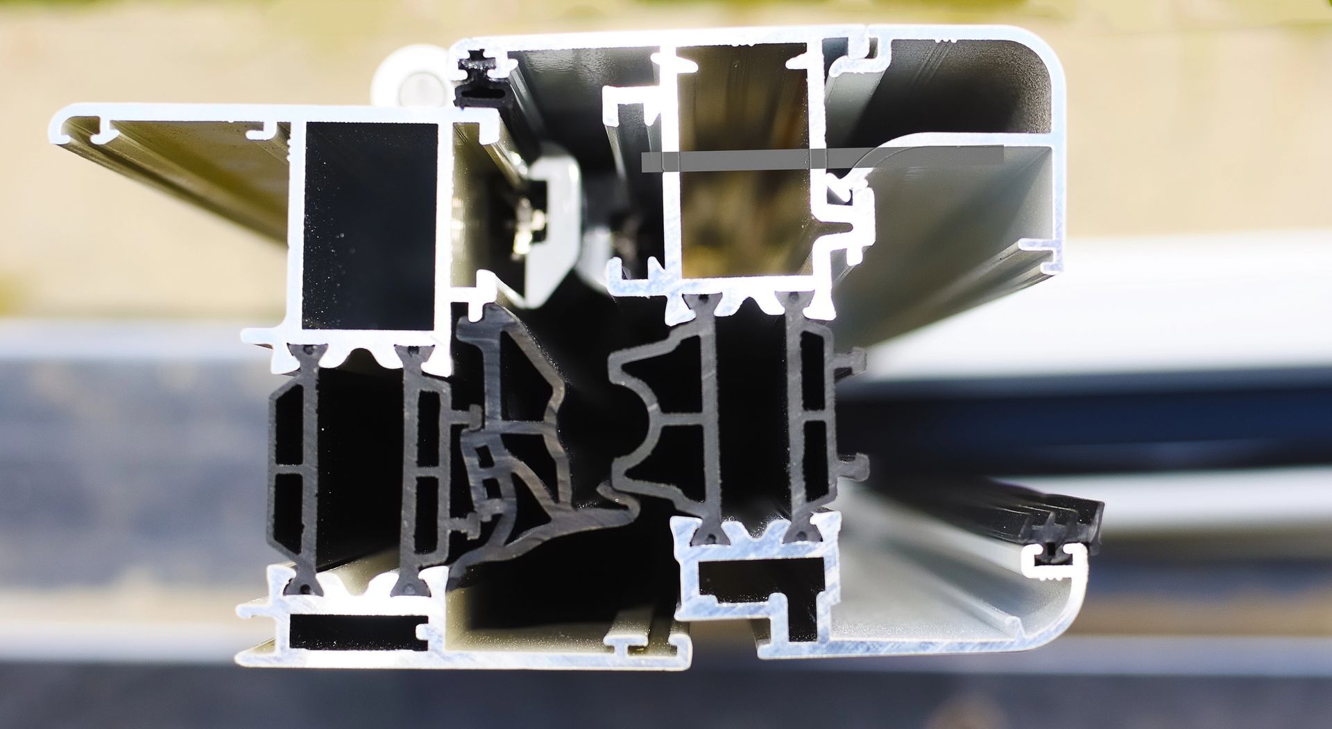 Sezione trasversale di un profilo per telaio di finestra in alluminio bianco e nero che mostra la sua complessa struttura interna e i tagli termici.