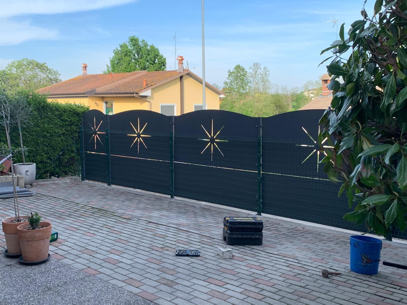 Recinzione decorativa in metallo nero con intagli a forma di stella, installata su un patio pavimentato nel cortile di un'abitazione privata.