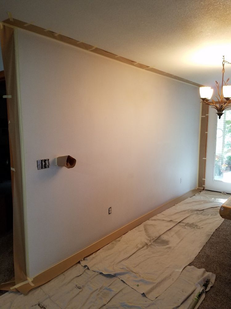 A large white wall is being painted in a living room.