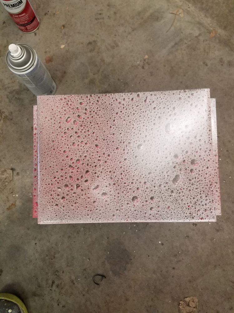 A spray can is sitting next to a piece of paper on the ground.