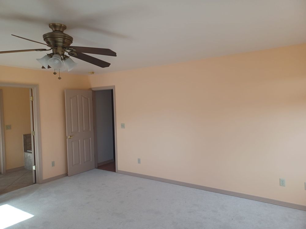 An empty room with a ceiling fan and a door