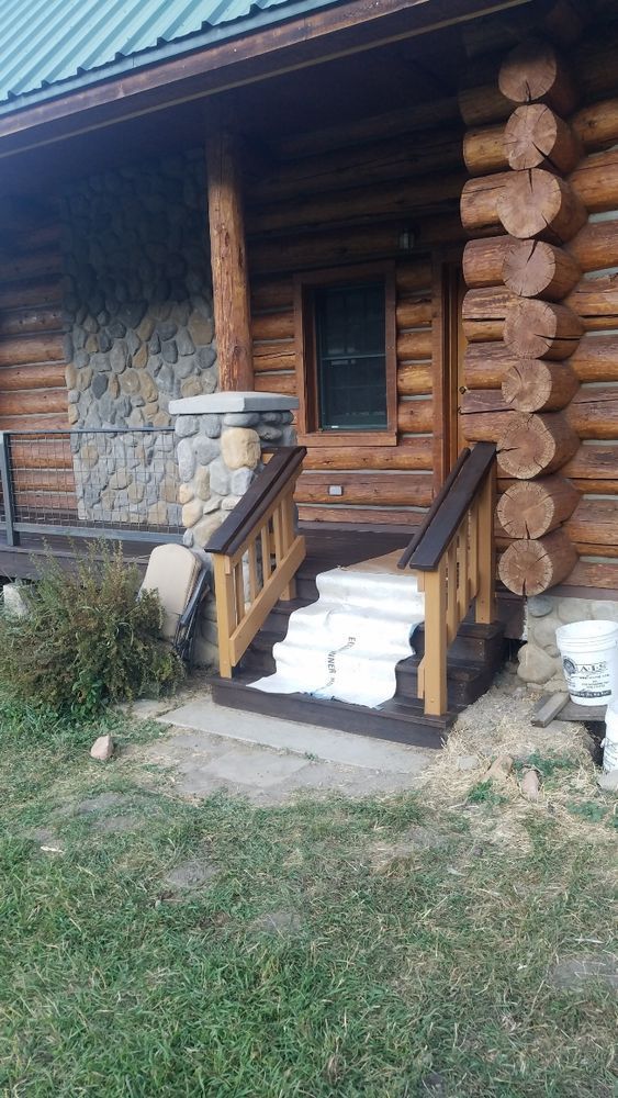 A log cabin with stairs leading up to the front door.