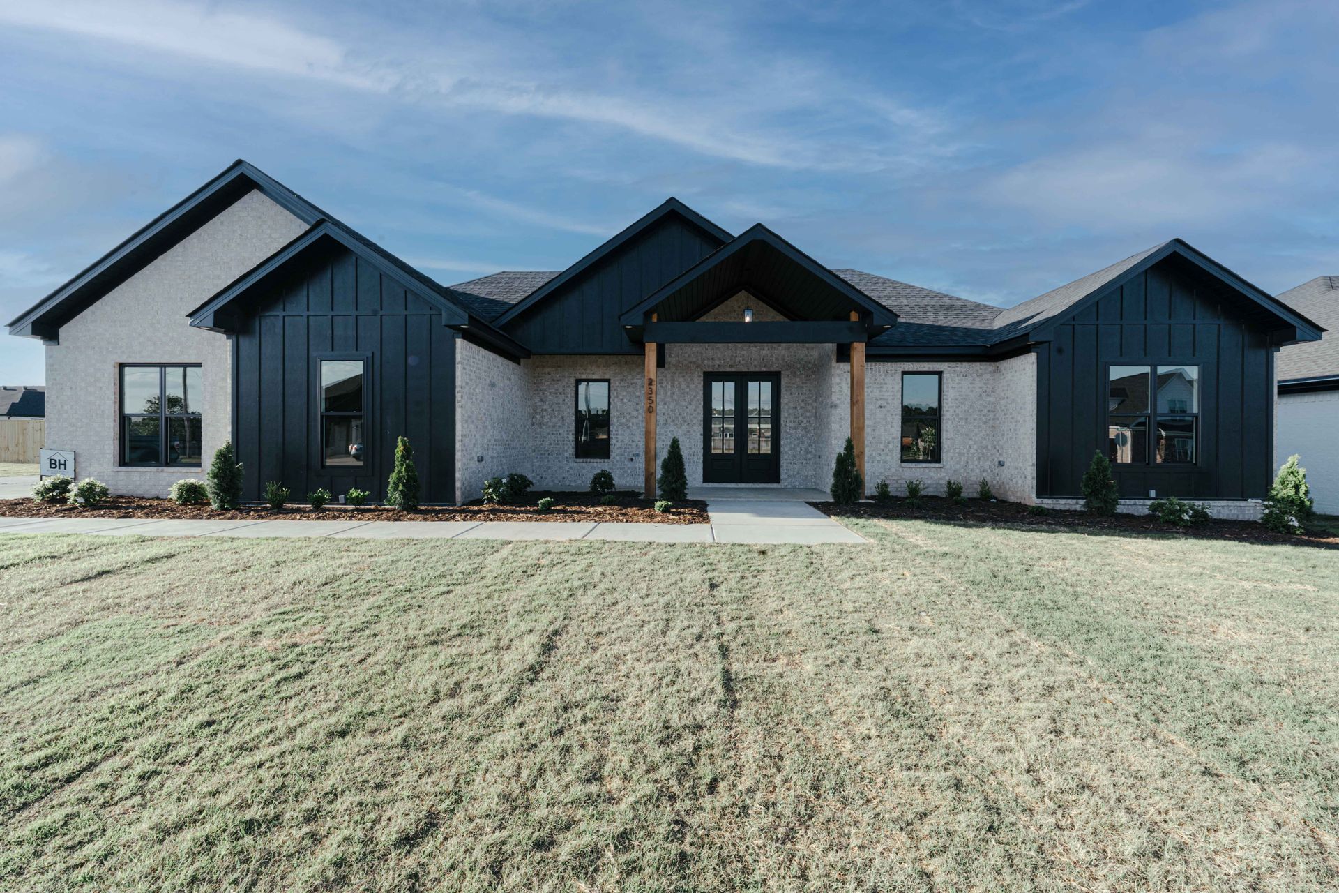 Exterior view of a modern farmhouse-style home with black siding and a welcoming front porch.