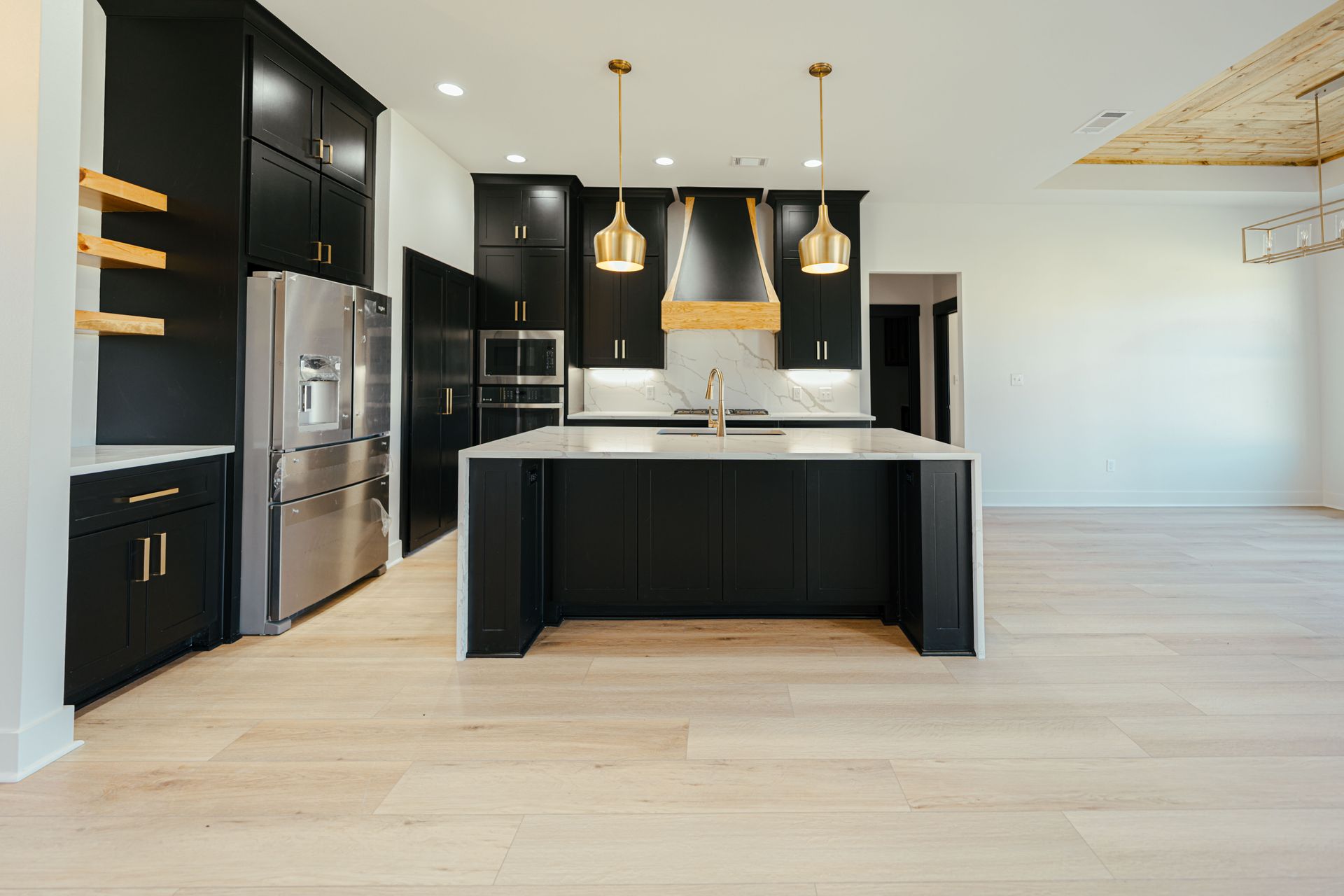Open-concept kitchen featuring black cabinetry, a large island, and gold accents.