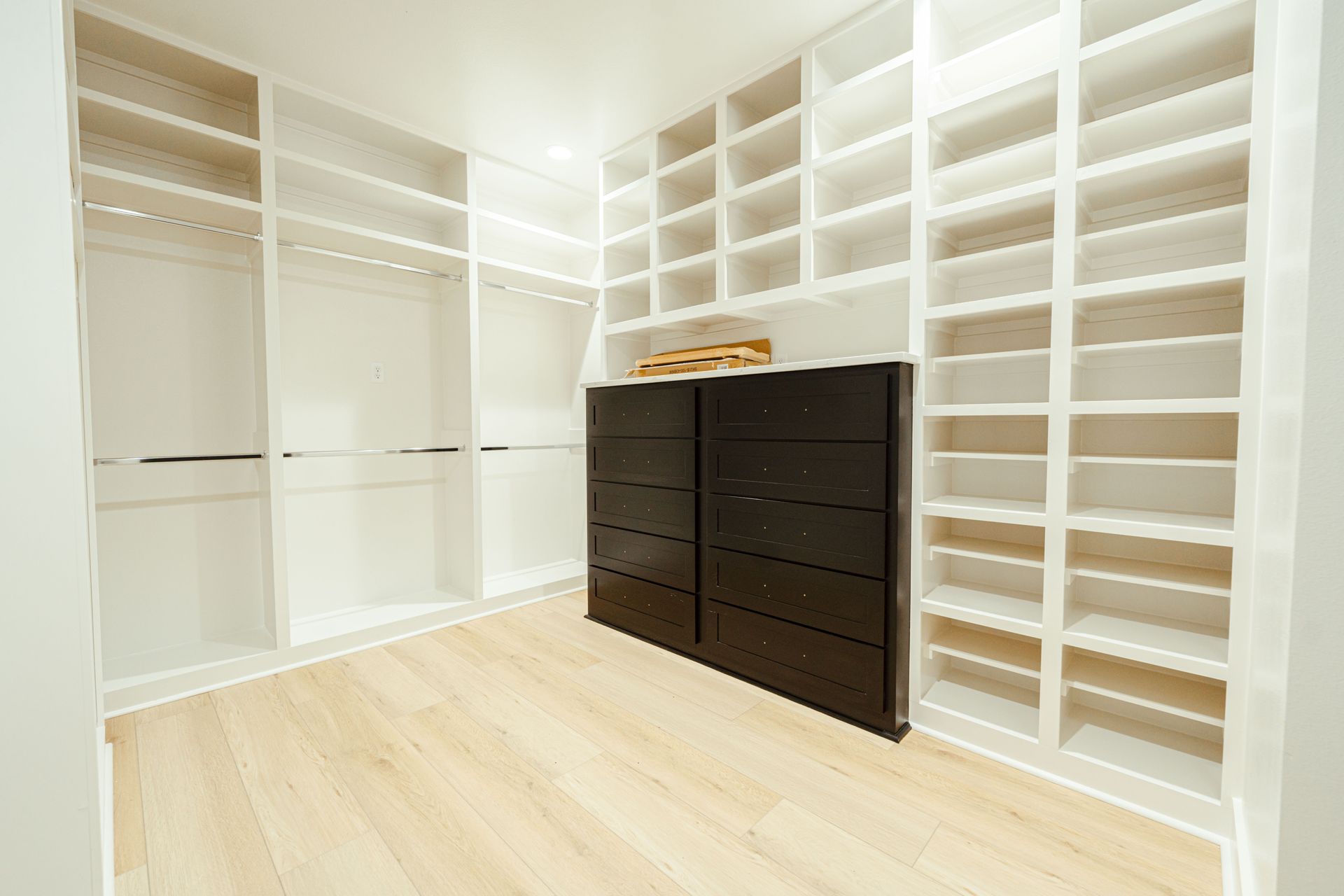 Walk-in closet with custom shelving and a built-in dresser.