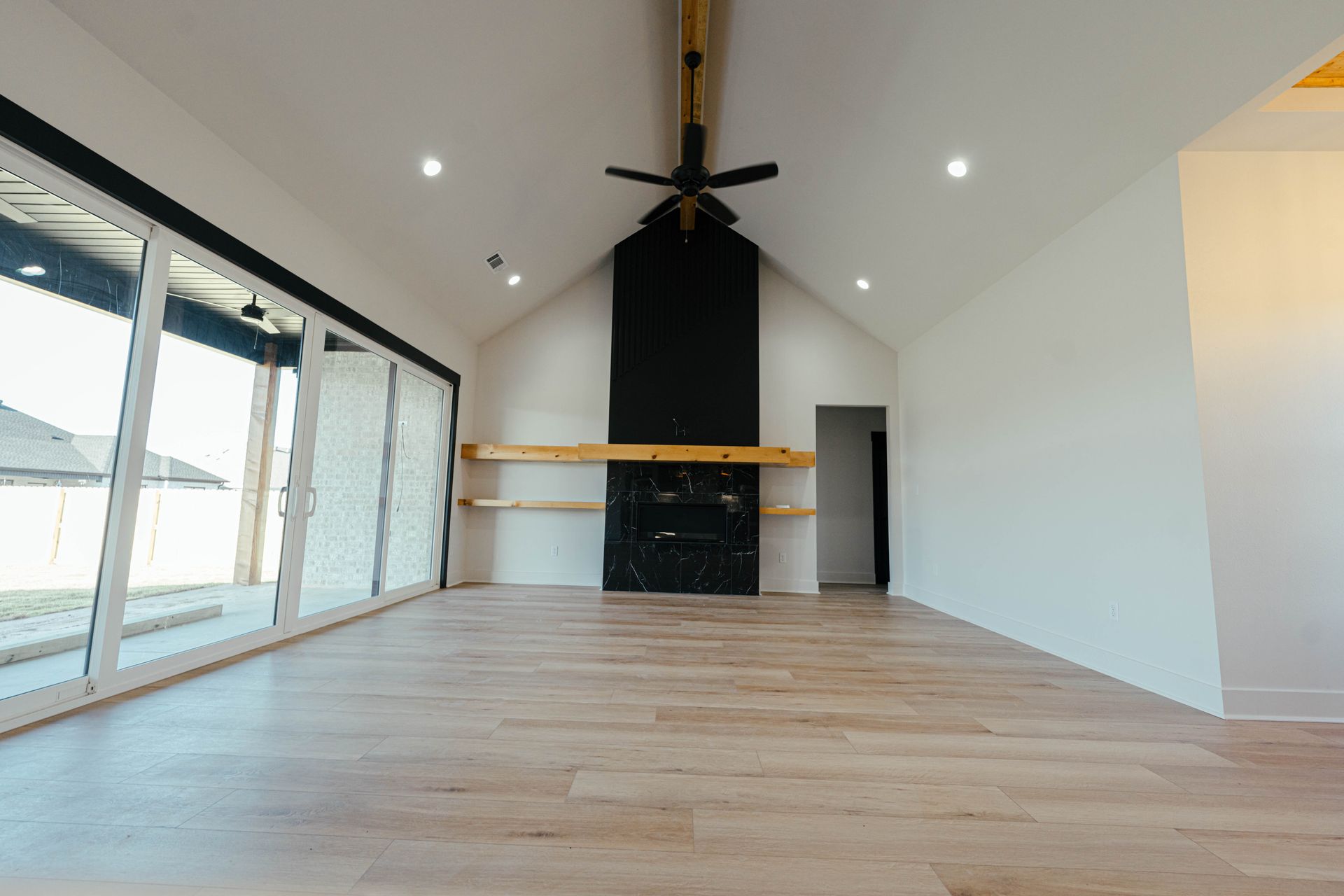 Spacious living room with vaulted ceiling, modern fireplace, and large sliding glass doors.