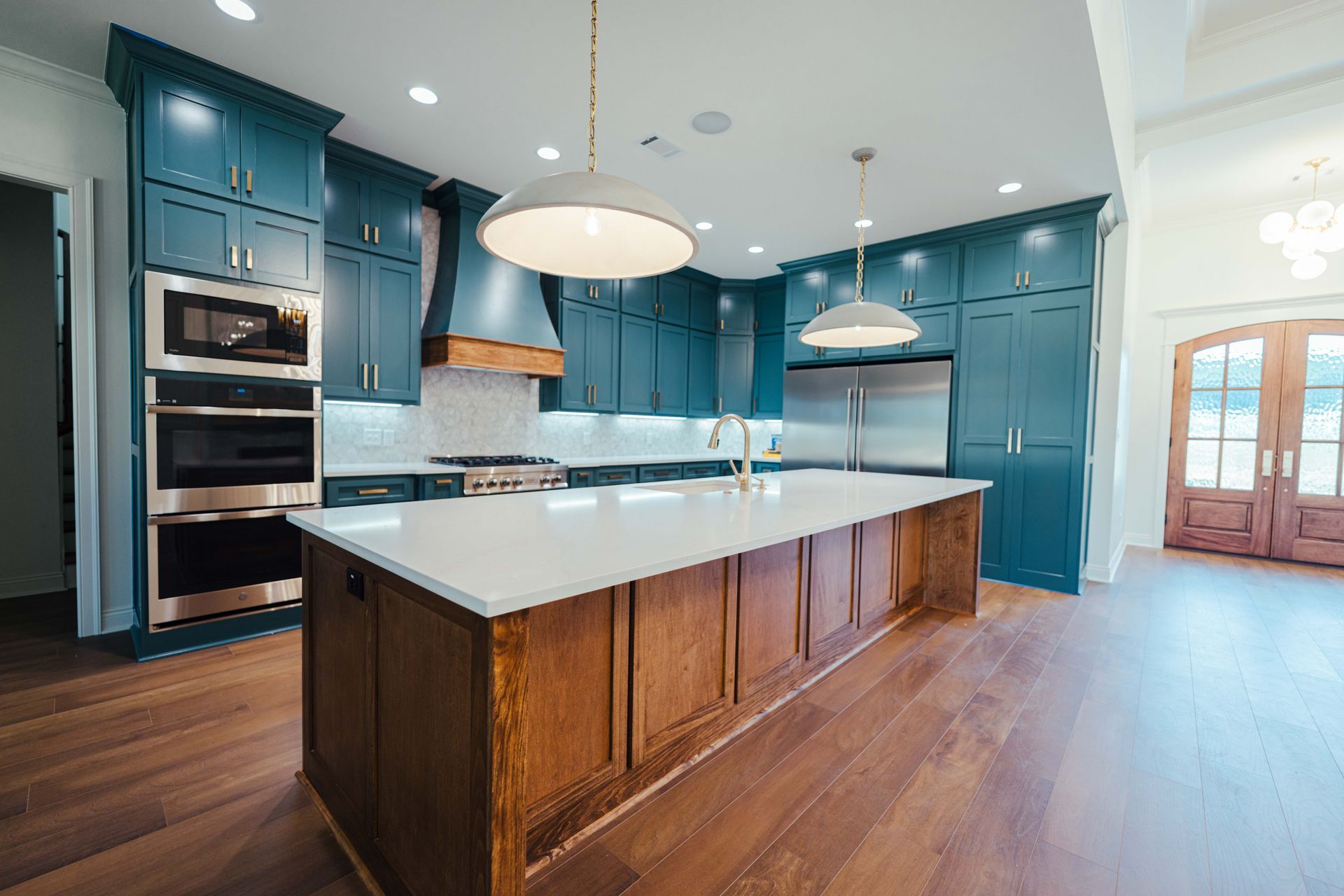 Custom kitchen with dark teal cabinets, large island, and wood accents for a warm, welcoming design.