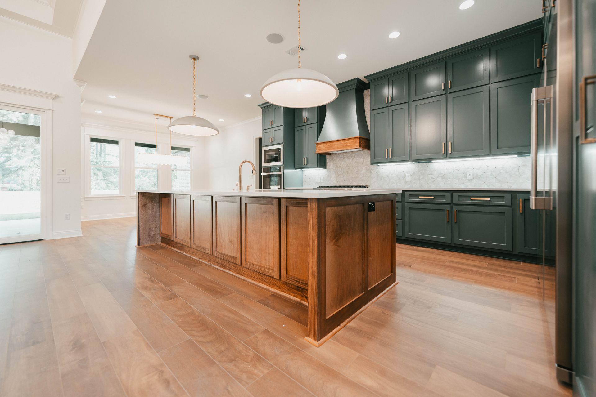 A large kitchen with a wooden island and dark cabinetry, featuring stainless steel appliances and bright open space.