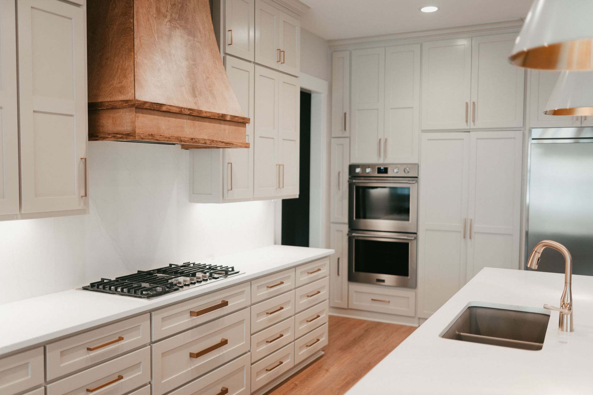 A modern kitchen with a sleek design, stainless steel appliances, and custom wood vent hood.
