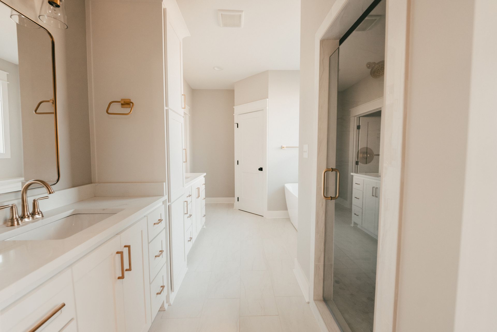 Bright and airy bathroom with white cabinetry and gold fixtures.