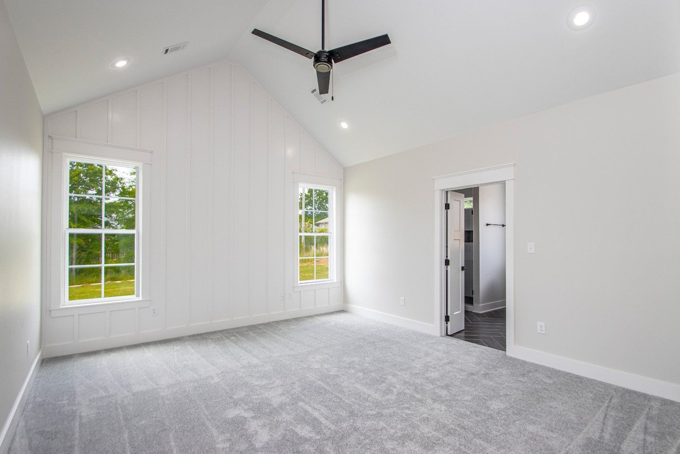 Bright bedroom with high ceilings, large windows, and gray carpet, ready for personal touches.