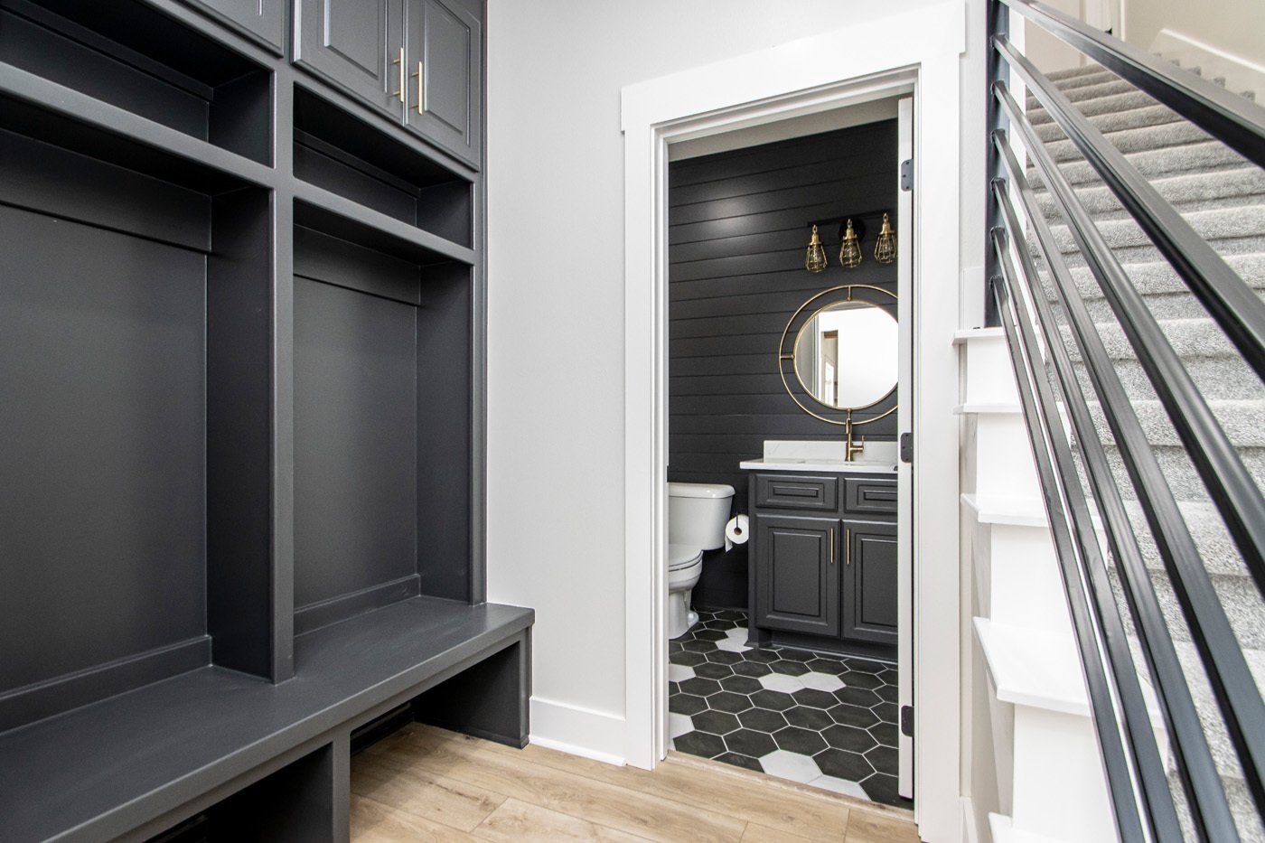 Entryway with black mudroom cabinetry, built-in bench, and adjacent bathroom featuring dark walls.