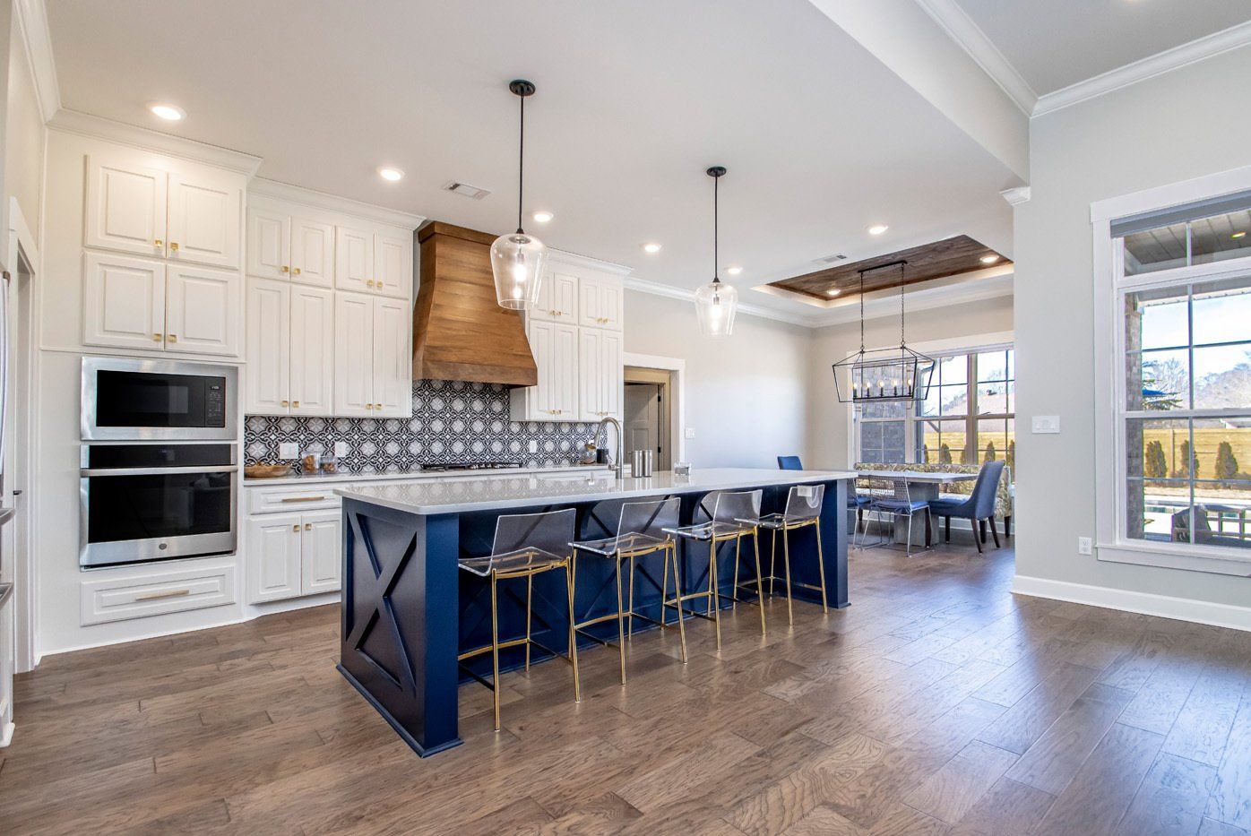Spacious kitchen featuring a large island with navy cabinetry and a unique wood accent range hood.