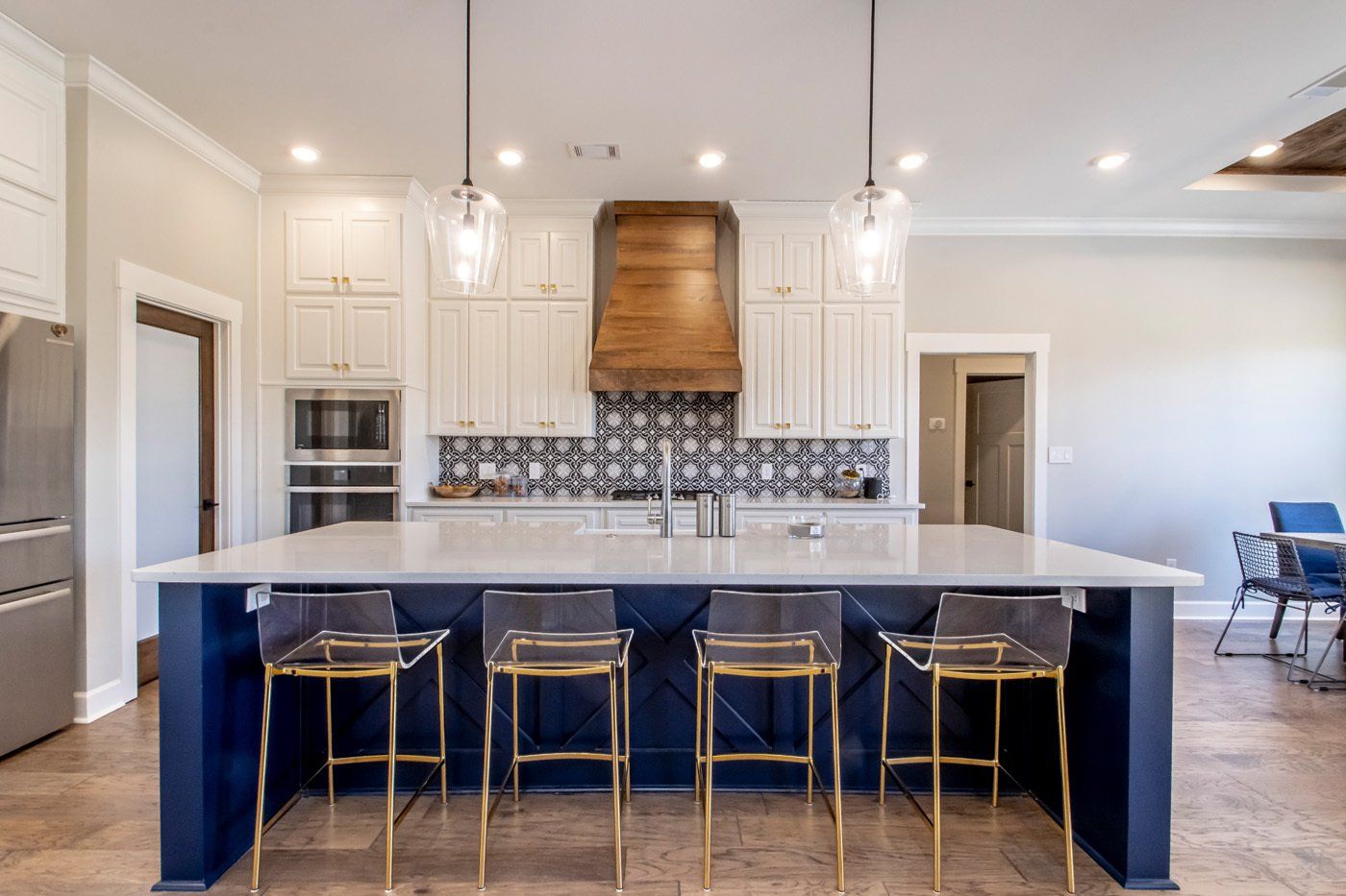 Modern kitchen with sleek navy cabinets, gold accents, and ample space for seating.