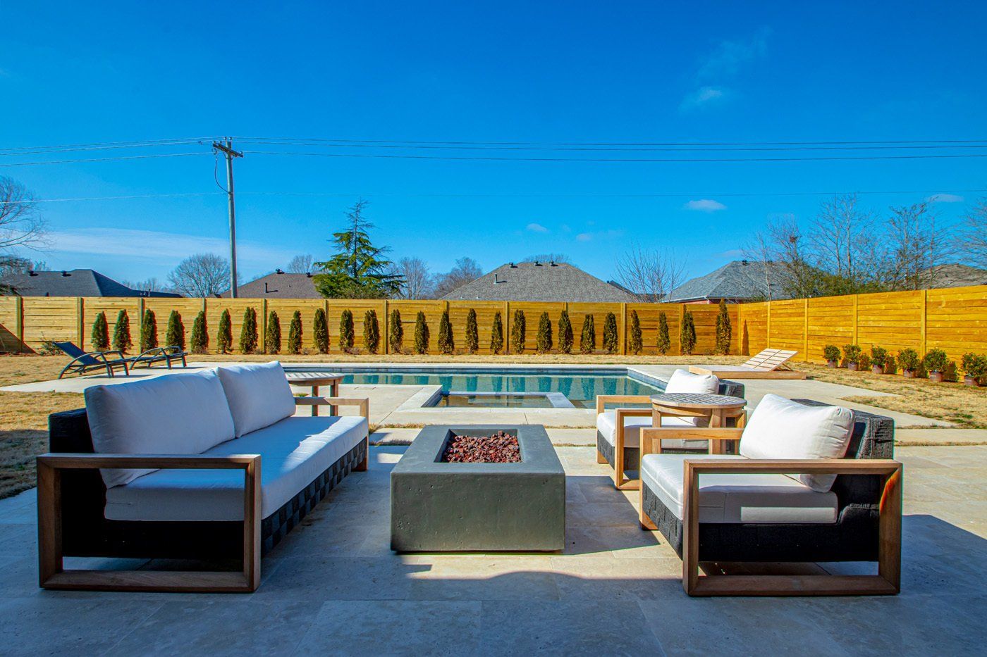 Outdoor lounge area with a cozy fire pit next to a pool, perfect for relaxation.