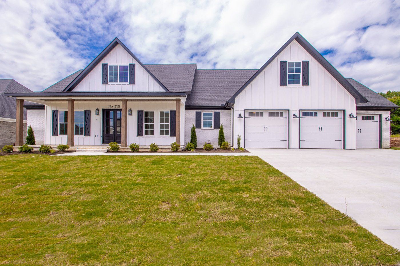 Front exterior of a custom home with a three-car garage and a spacious lawn.