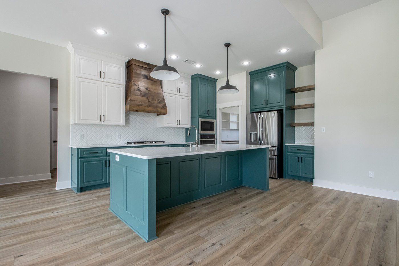 Contemporary kitchen with a large teal island, white cabinetry, and stainless steel appliances.