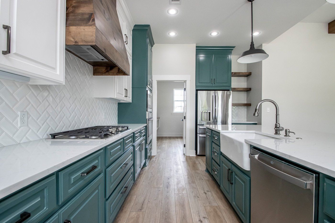 Modern kitchen with teal cabinets, white countertops, and a wood-trimmed vent hood.